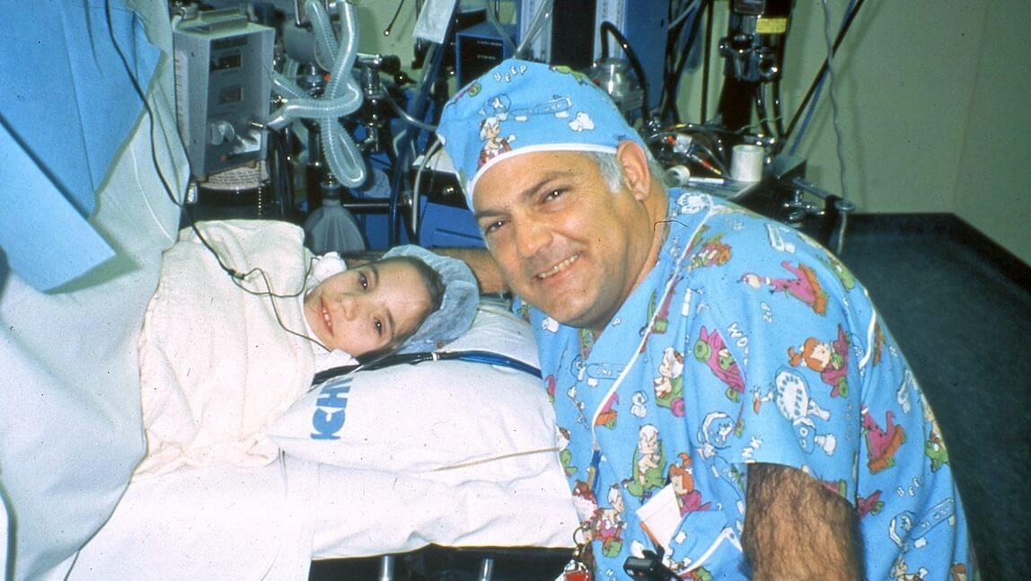 a doctor in scrubs leaning over a young patient in a bed