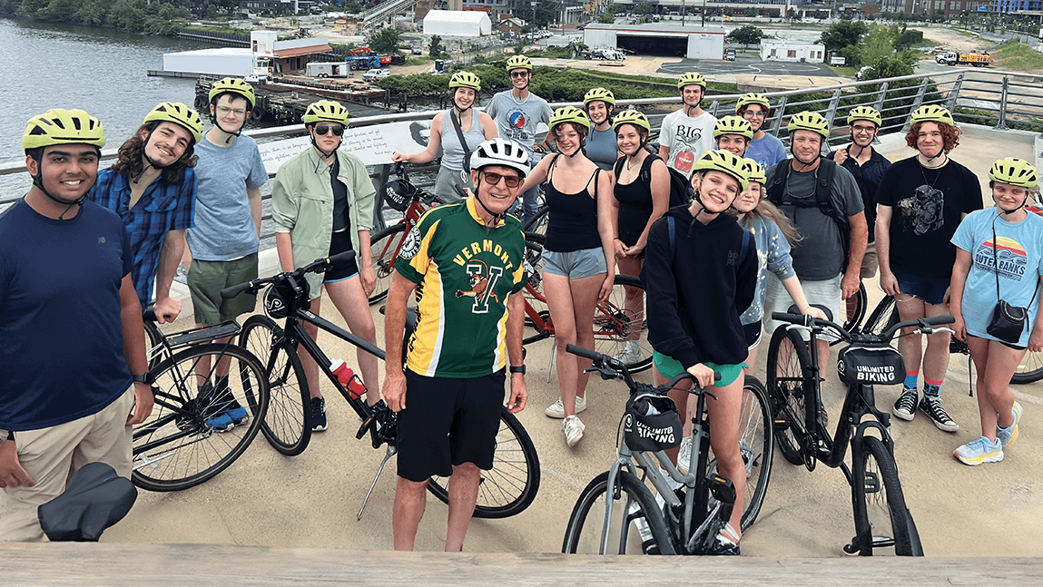 a large grooup of bicyclists stand with their bikes