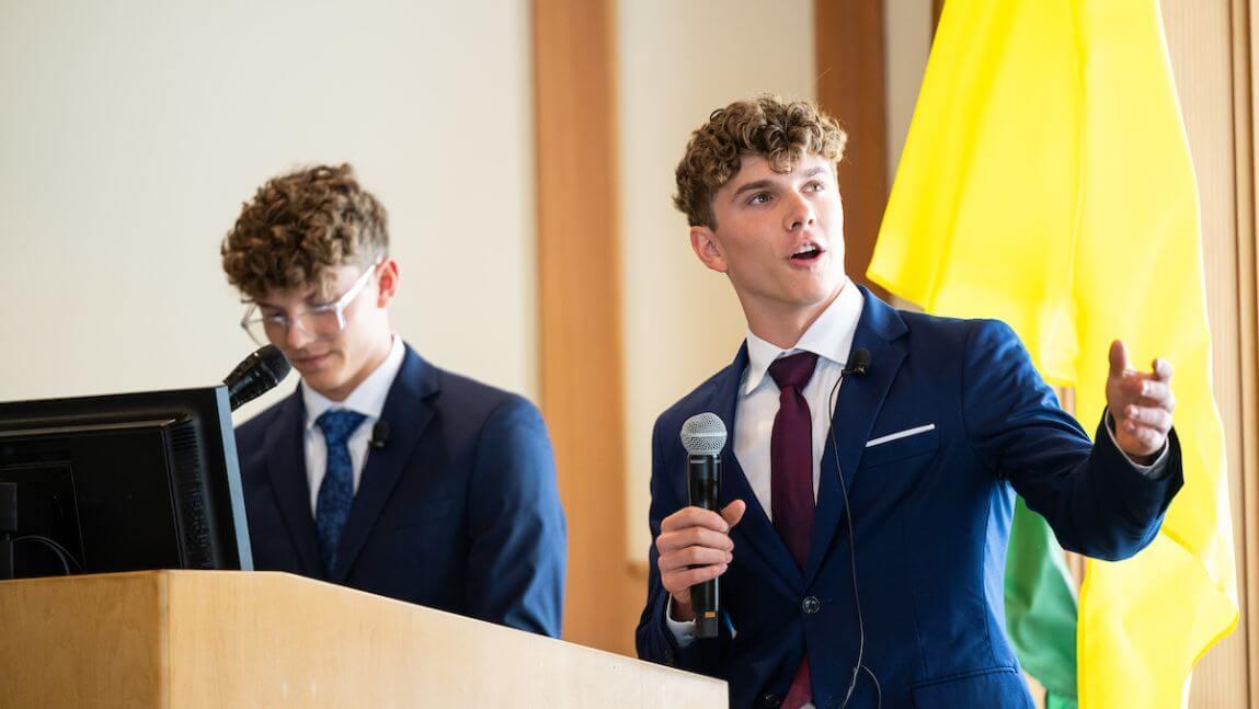 Two students wearing suits give a presentation 